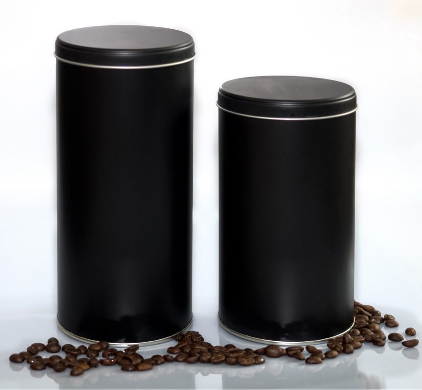 Zwei schwarze Aroma Kaffeedosen zur Kaffeeaufbewahrung mit verstreuten Kaffeebohnen